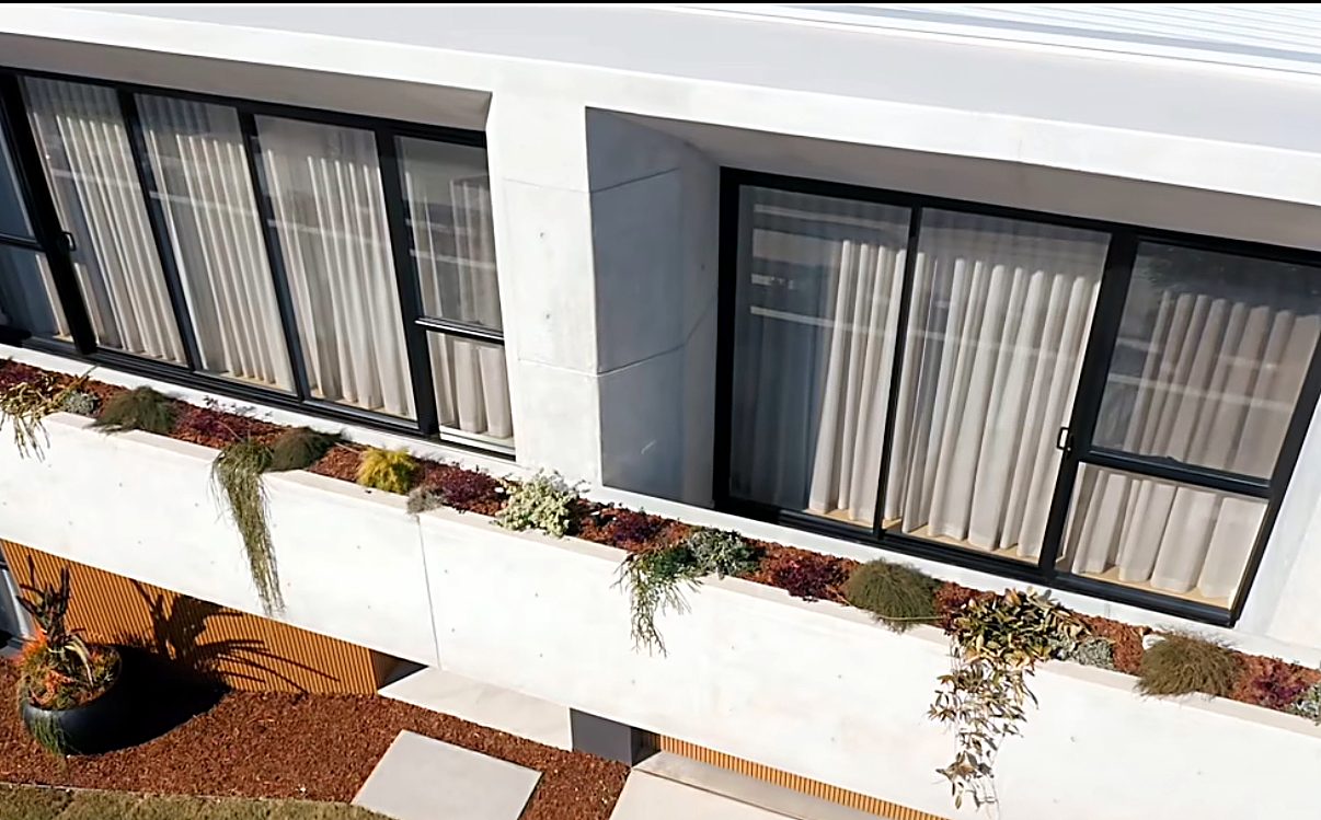 Full home renovation with concrete facade, black-framed glass and planter boxes